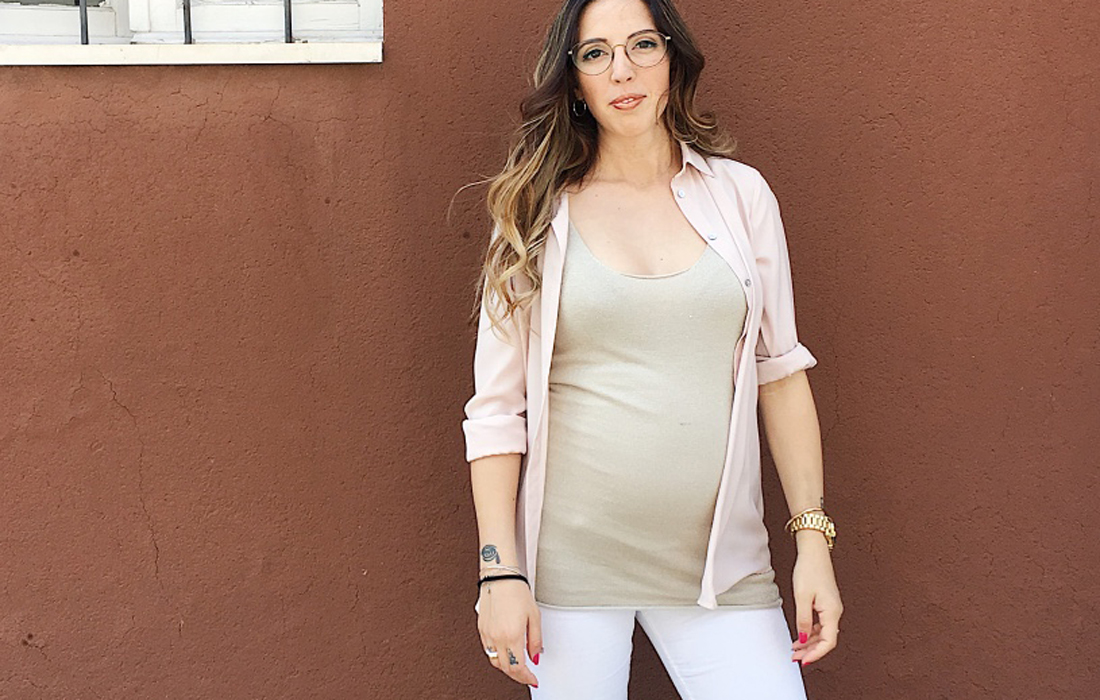 Donna incinta di 25 settimane, sullo sfondo un muro color mattone.
