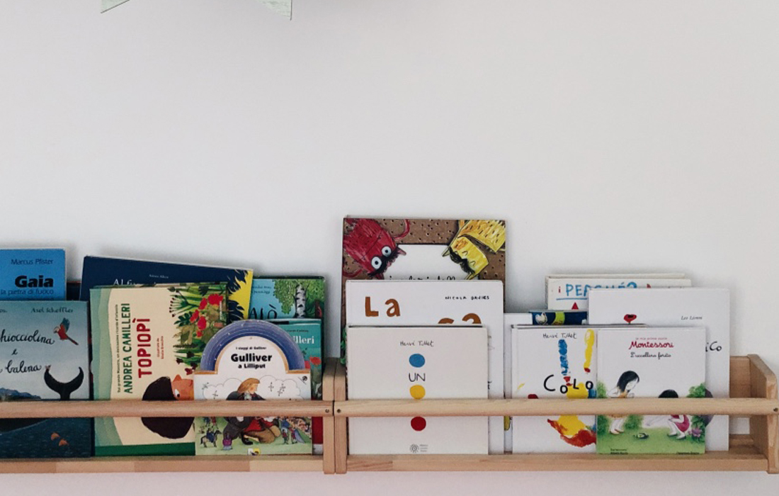 libreria frontale ikea in legno appesa al muro sulla quale sono riposti diversi libri da bambino.